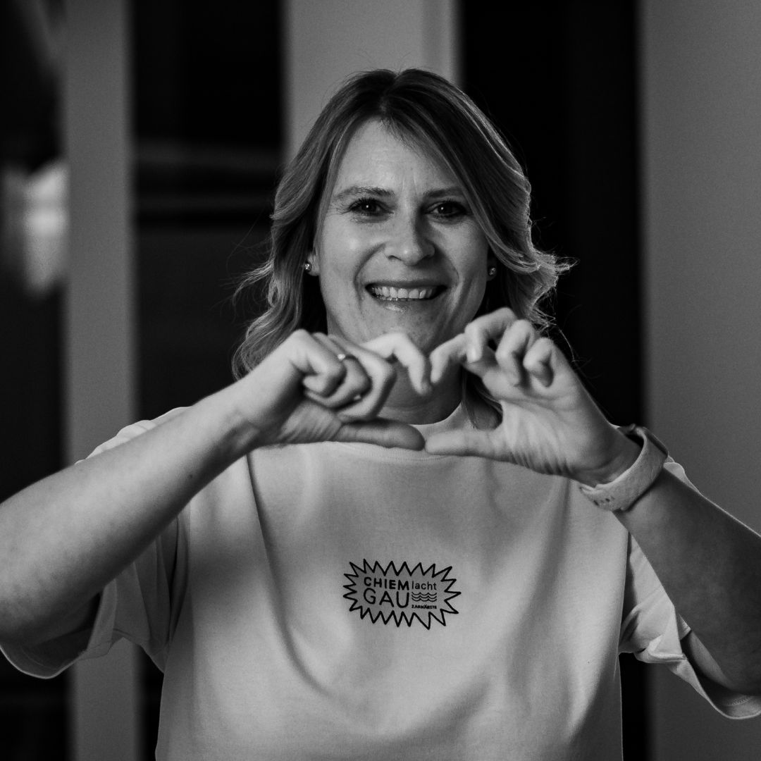 Mitarbeiterin von Chiemgau Lacht Zahnärzte formt mit den Händen ein Herz im Praxisflur