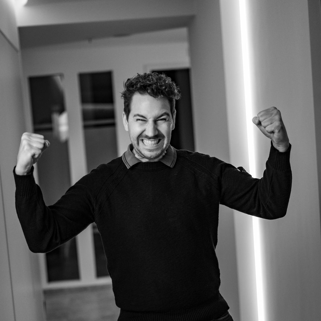 Teammitglied der Zahnarztpraxis Chiemgau Lacht mit erhobenen Fäusten im Praxisflur